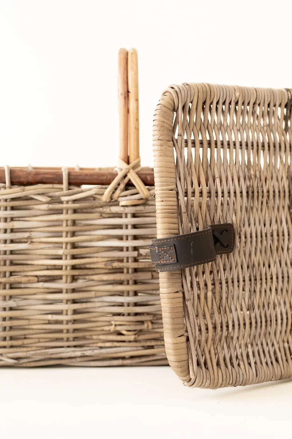 Wicker basket with a brown strap on a white background