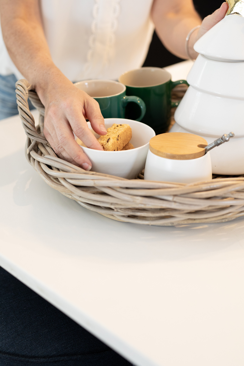 Person holding a cookie over a bowl with tea and cookies on a table in Ratan Tray.