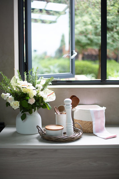 Decorative items in Rattan tray on a windowsill with a view of greenery outside