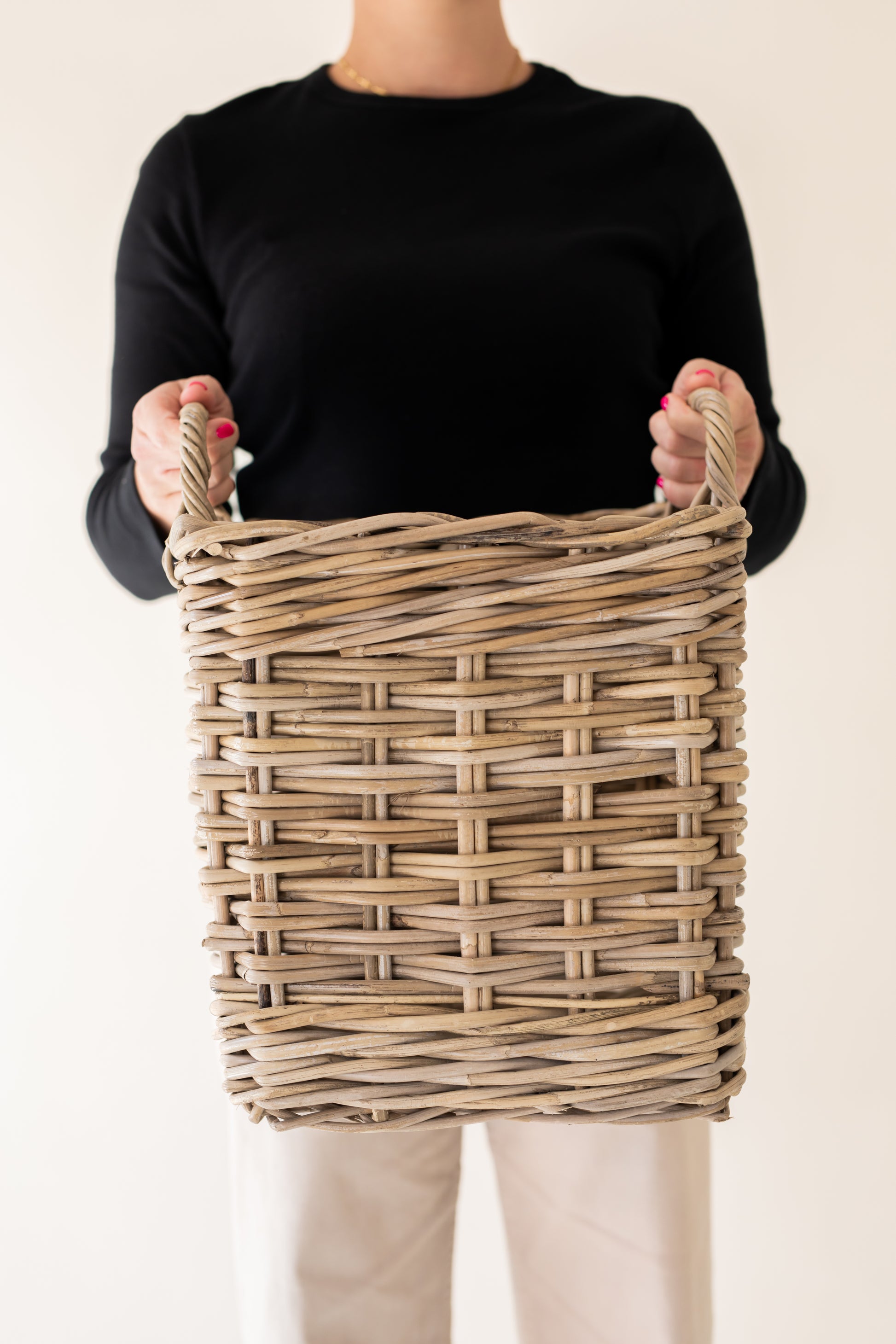 Person holding a rattan basket against a plain background