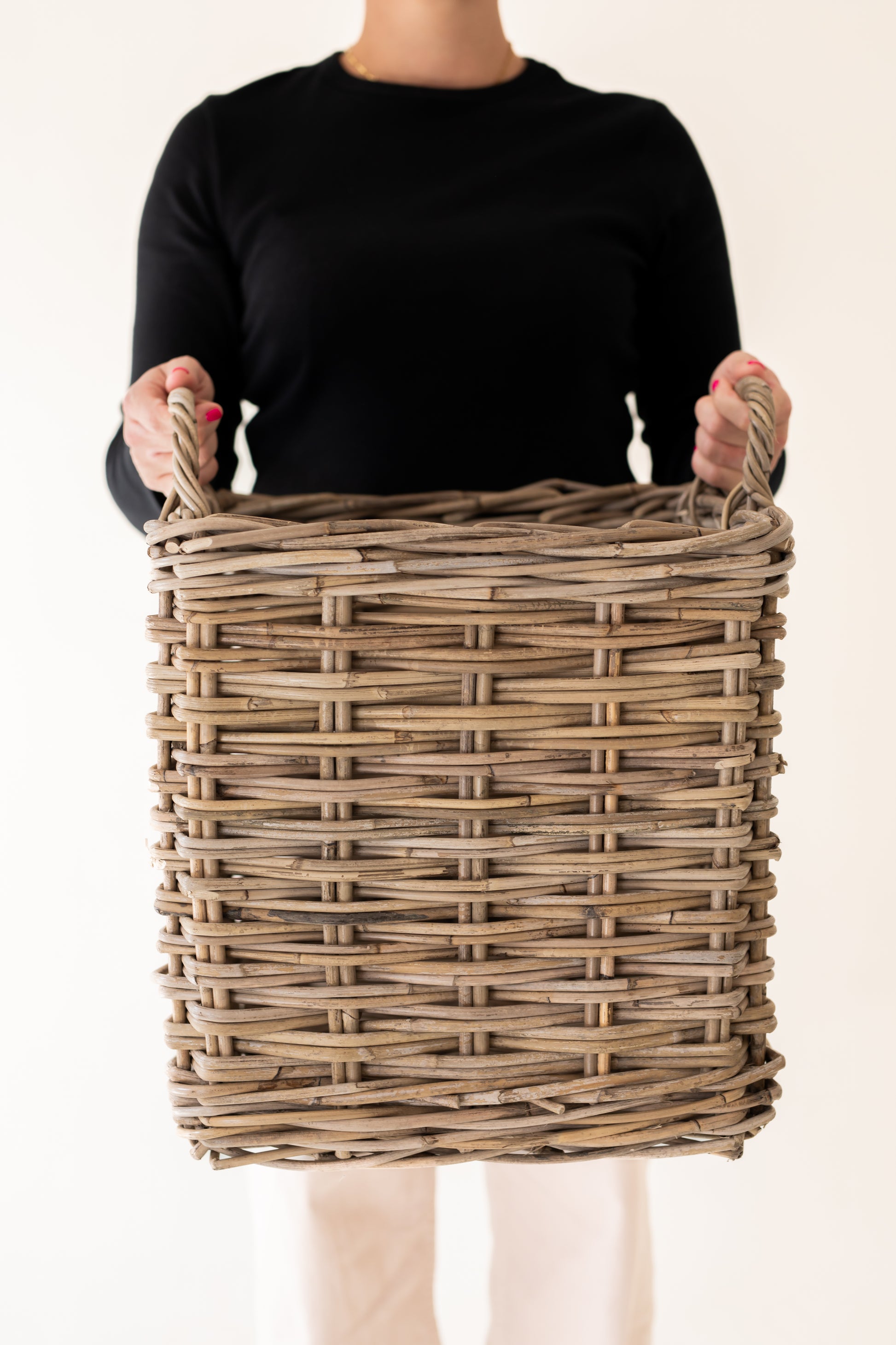 Person holding a medium basket against a plain background