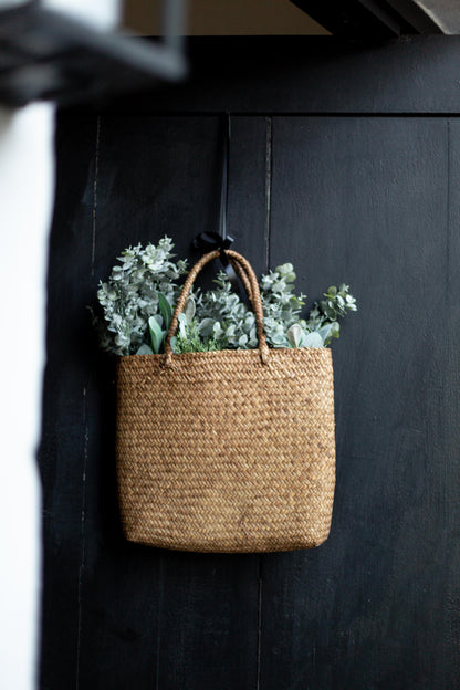 Woven basket with plants hanging on a dark wooden wall