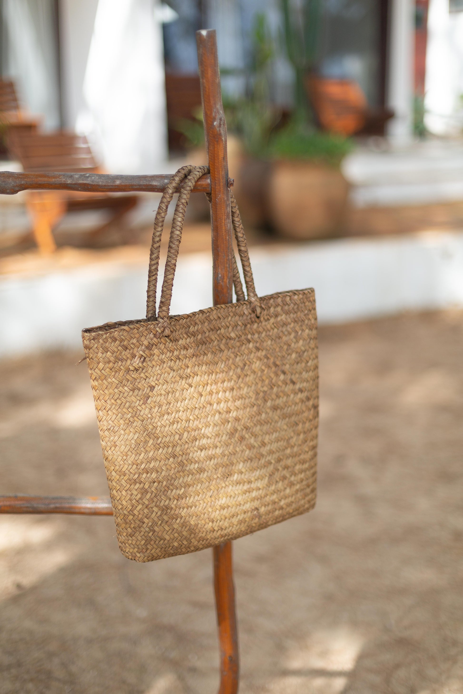 Woven sea gras tote hanging on a wooden chair outdoors