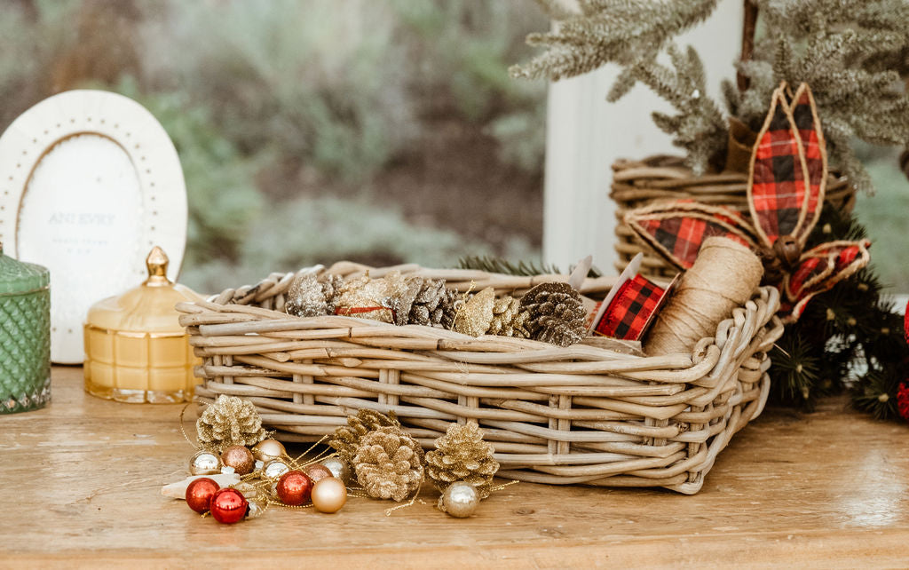 Rattan basket with decorative items on a wooden surface, surrounded by Christmas decorations.