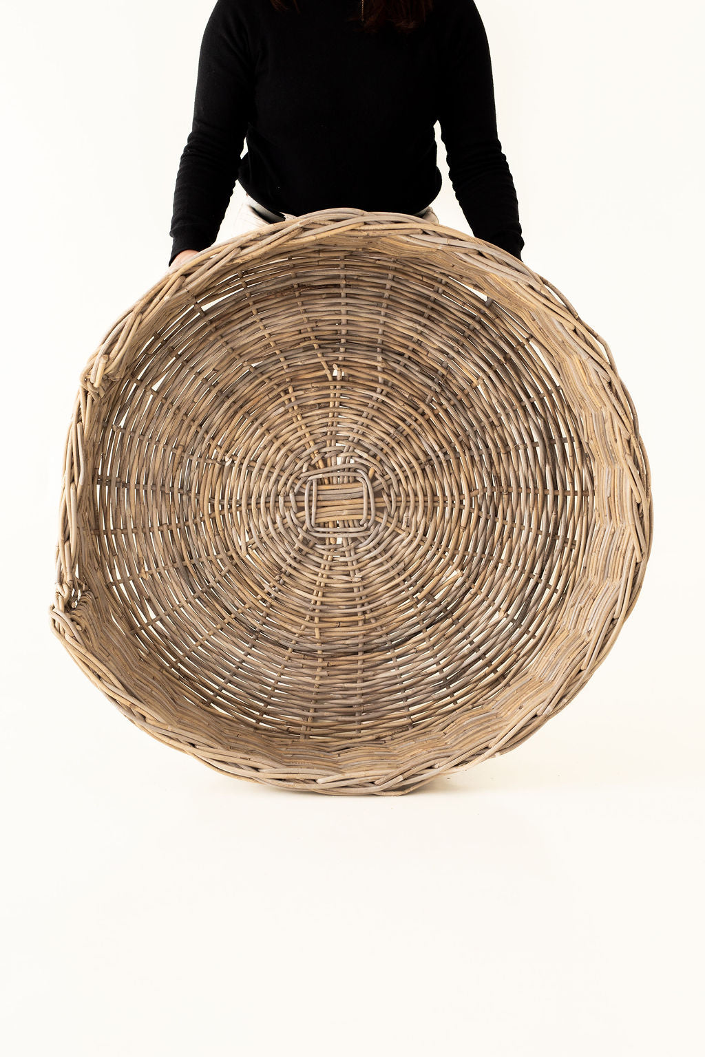 Large woven basket held by a person on a white background
