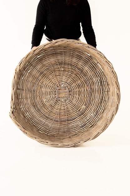 Large woven basket held by a person on a white background