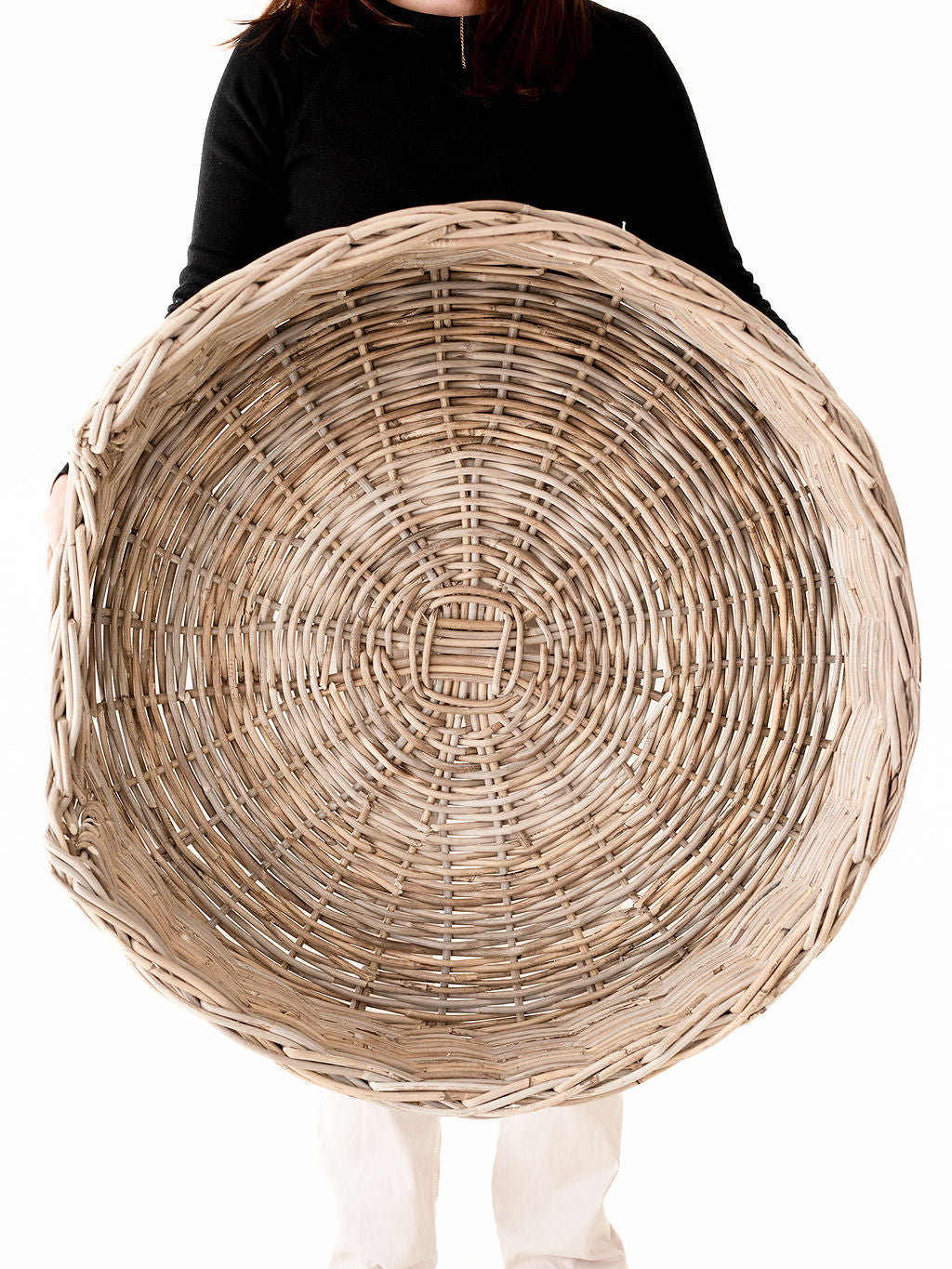 Person holding a large woven basket against a white background