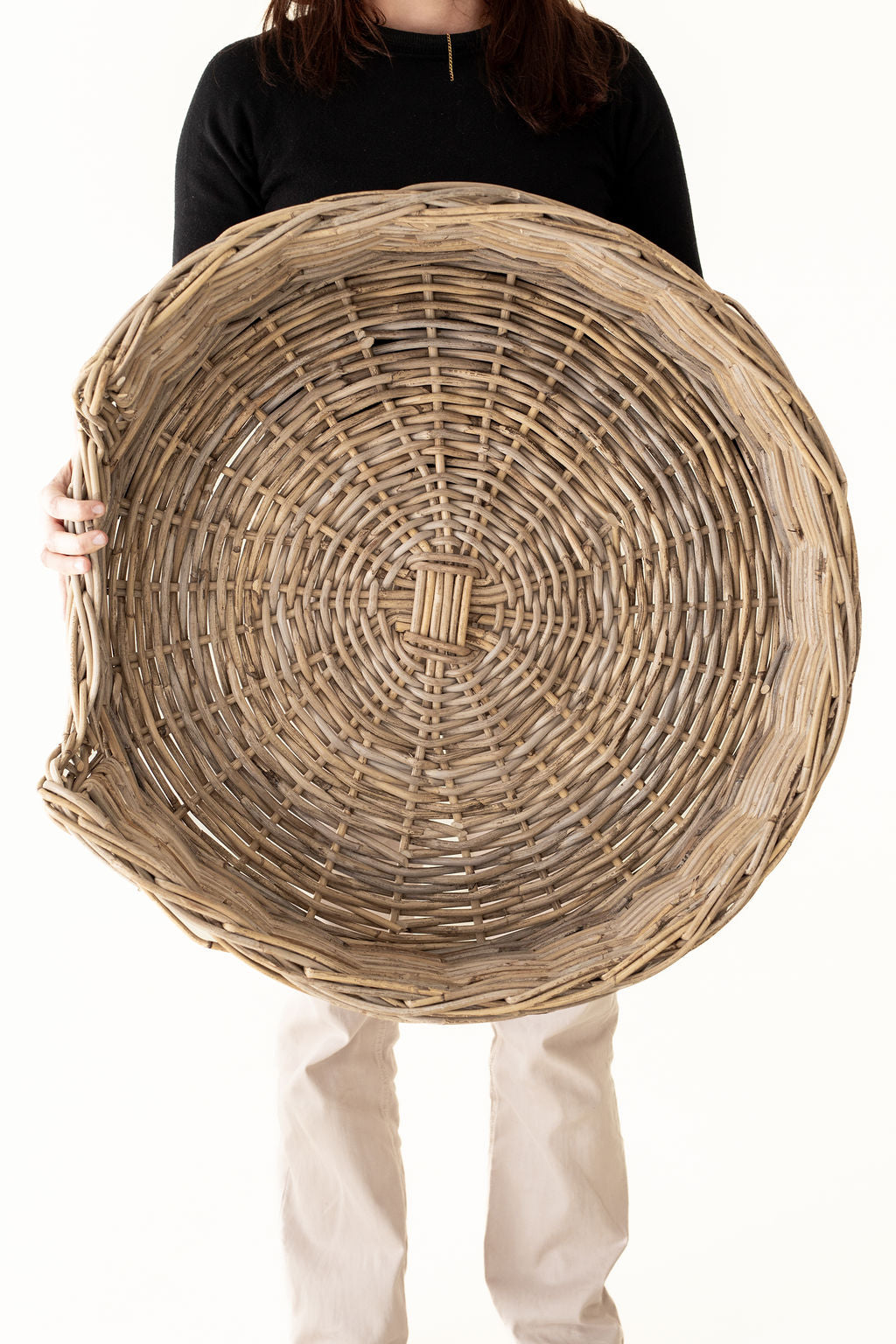 Person holding a large woven basket against a white background