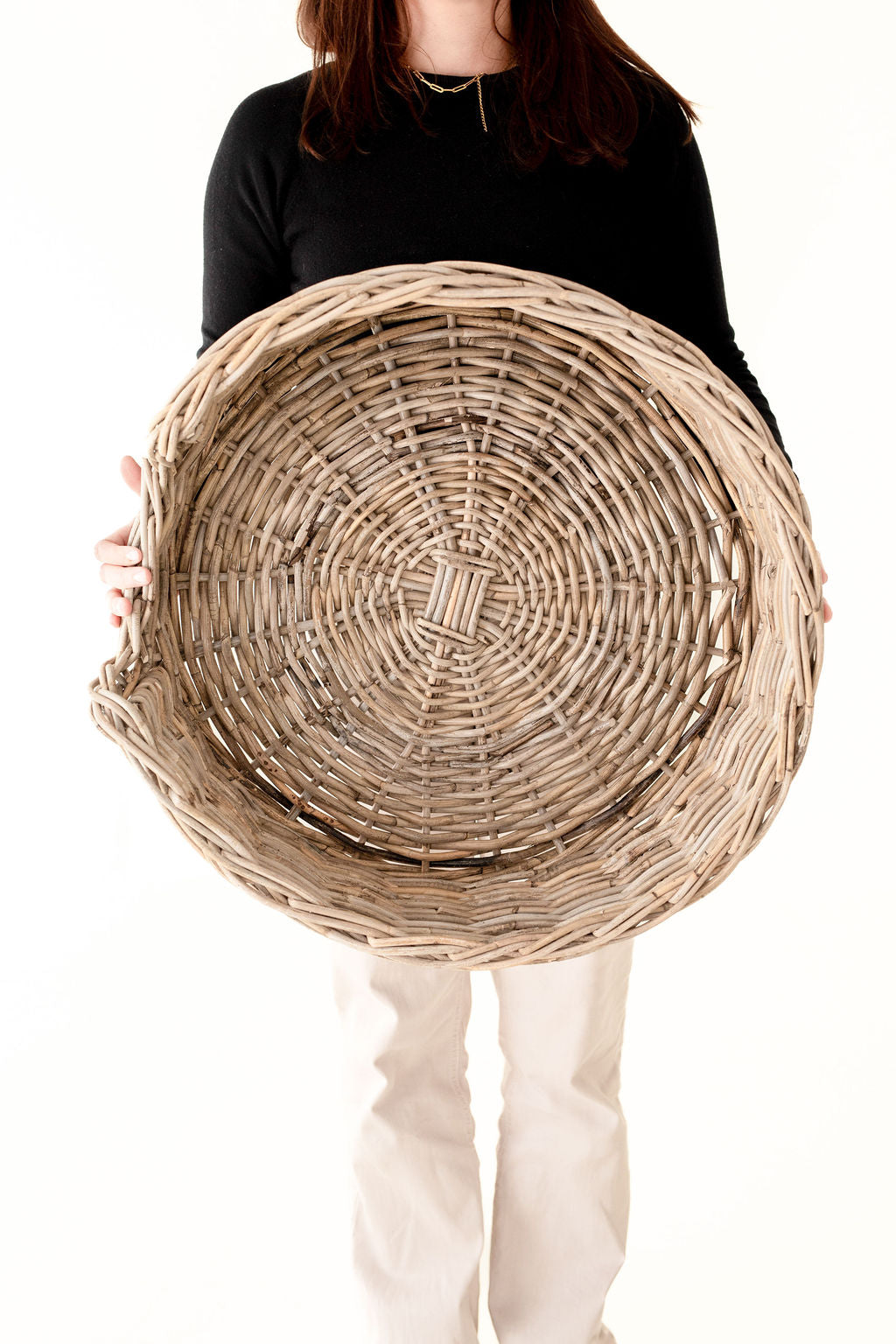 Person holding a small woven basket against a white background